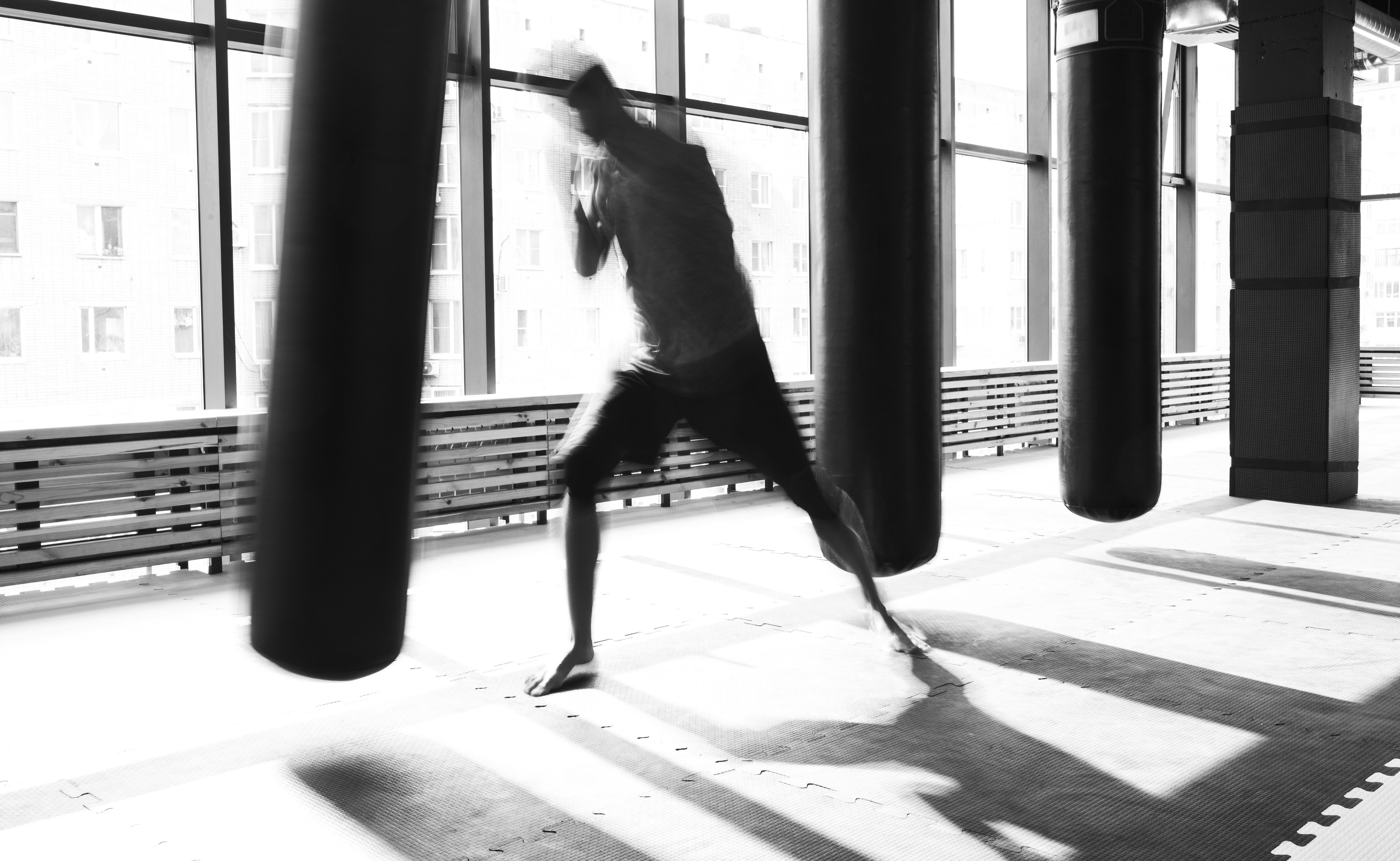 A boxer moves through a heavy-bag drill in a sunlit gym