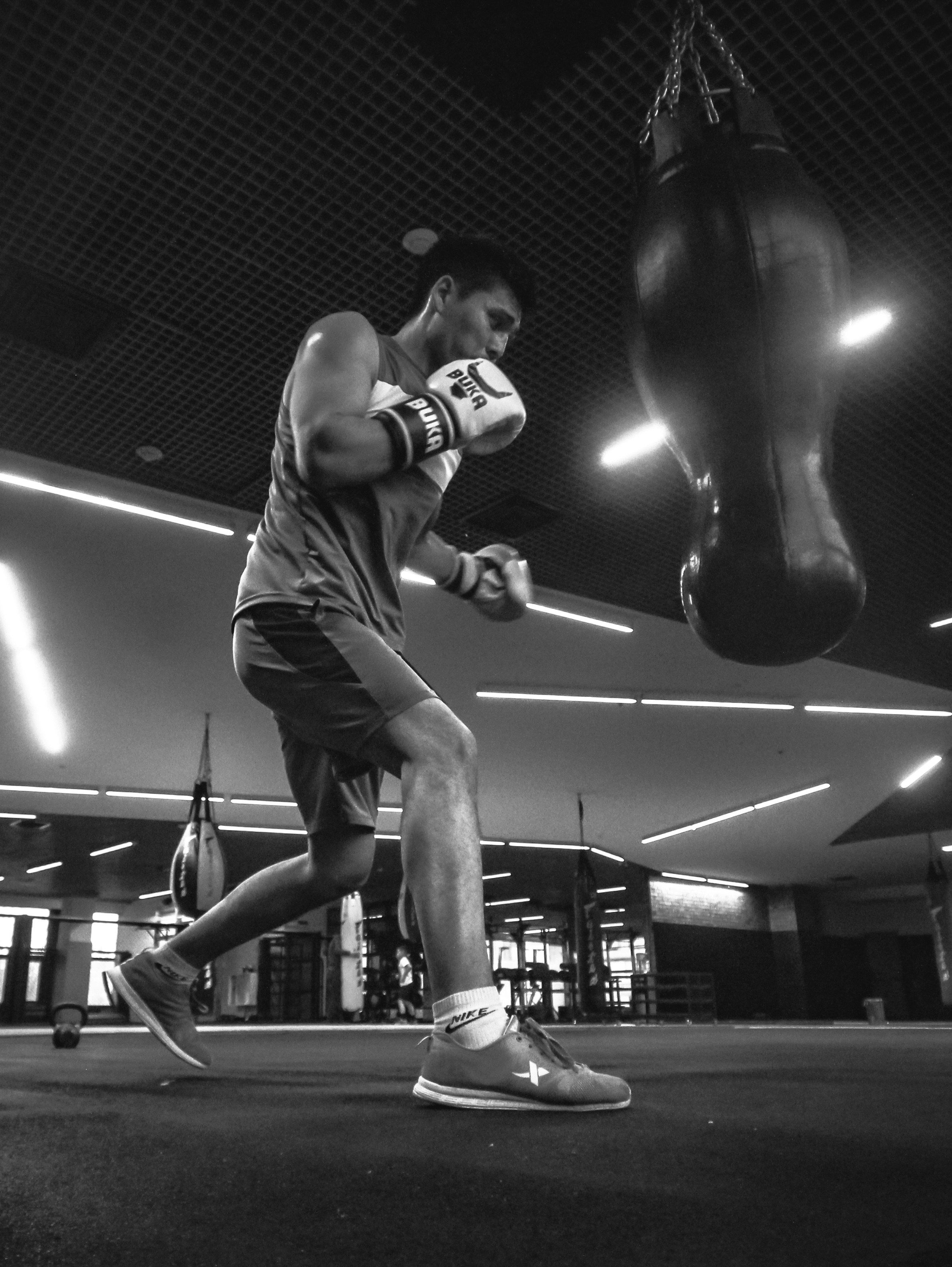 A boxer circles a heavy bag during gym training