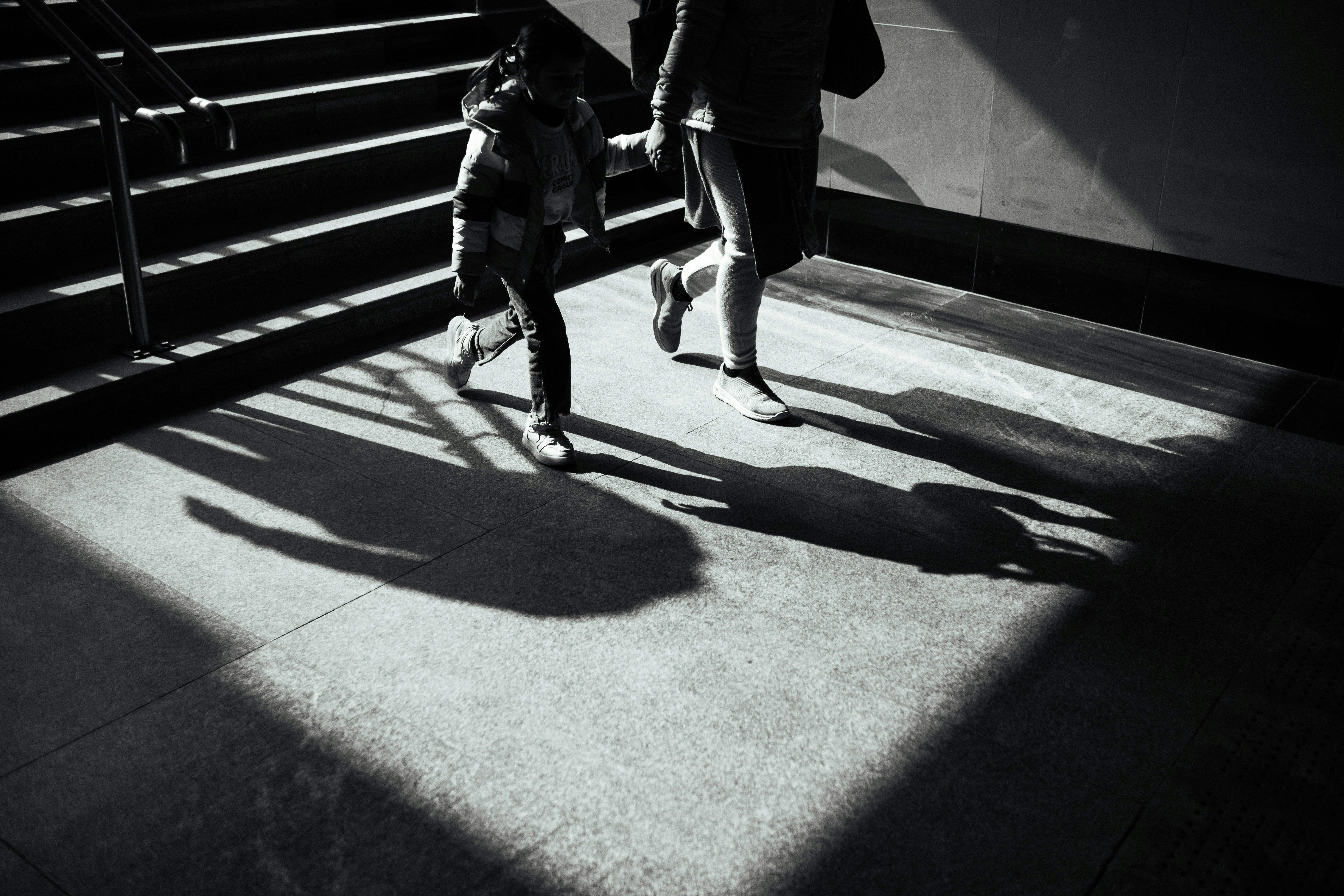 A child and an adult run through a sunlit stairway